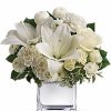 White roses with soft greenery arranged in a vase.