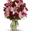 Classic bouquet of red roses arranged with greenery in a clear vase.