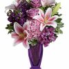 Lavender and pink flowers arranged in a violet vase.