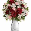 Bouquet of red roses with greenery in a clear vase.