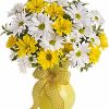 White and yellow daisy bouquet with greenery arranged in a vase.