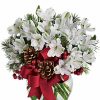 White alstroemeria flowers with winter greenery in a vase.