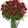 Two dozen long-stemmed red roses arranged in a clear glass vase.
