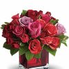 Romantic bouquet of red roses and pink flowers arranged with greenery.