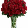 Long-stemmed red roses arranged with greenery in a clear vase.