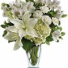 White rose bouquet with greenery arranged in a vase.