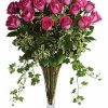 Two dozen hot-pink roses with cascading ivy in a clear glass vase.