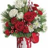 Red and white holiday bouquet with candy-cane accents and greenery.