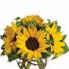 Cheerful arrangement of bright-yellow flowers accented with fresh greenery