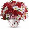 Mixed bouquet of red and pink roses with greenery in a glass vase.