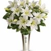 Sympathy bouquet of white lilies and roses arranged with greenery.