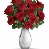 Elegant bouquet of twelve red roses with greenery in a glass vase.