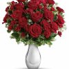 Deluxe bouquet of vibrant red roses arranged with lush greenery in a clear vase.