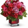Elegant bouquet of red roses with greenery arranged in a glass vase.